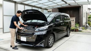 清潔な日本の自宅ガレージでブラックの新型40系ヴェルファイアZ Premierのボンネットを開けエンジンルームを点検しながら微笑む若い日本人男性